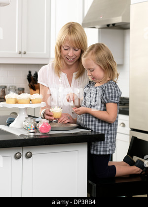 Madre e figlia come decorare le tortine nel concetto aperto cucina, Toronto, Ontario, Canada Foto Stock