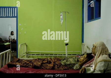 Jul 19, 2006; Ciamis, West Java, INDONESIA; tsunami indonesiano sopravvissuto Siti Aidah stabilisce sul letto dopo aver ricevuto un trattamento medico come sua parente sembra dopo la sua presso il public health center di Pangandaran, Ciamis, West Java, Indonesia, Martedì, luglio 18, 2006. Un tsunami che ha colpito le coste dell'isola indonesiana di Giava e ha preso più di 550 vite, lasciando più di 600 feriti Foto Stock