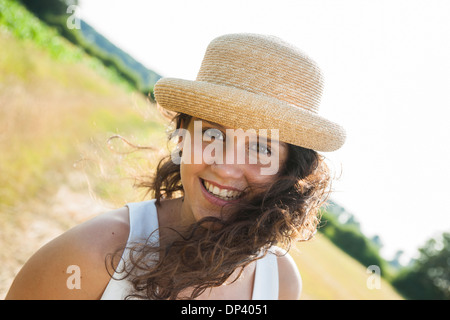 Close-up ritratto della ragazza adolescente in piedi in campo, indossare un cappello di paglia, sorridente alla fotocamera, Germania Foto Stock