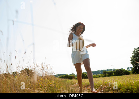 Adolescente ragazza con cappello di paglia e camminare in campo sul giorno di estate, Germania Foto Stock