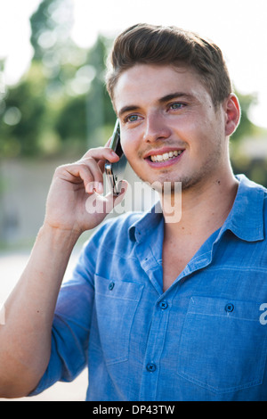 Giovane uomo tramite telefono cellulare all'aperto, Germania Foto Stock