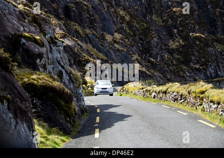 Auto sulle strette a due vie in discesa su strada il Conor Pass da Dingle town a Dunmore Testa, penisola di Dingle, nella contea di Kerry, Irlanda Foto Stock