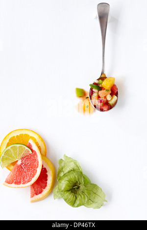 Vista aerea di agrumi Gazpacho sul cucchiaio con fette di agrumi e Tomatillo, sfondo bianco Studio Shot Foto Stock