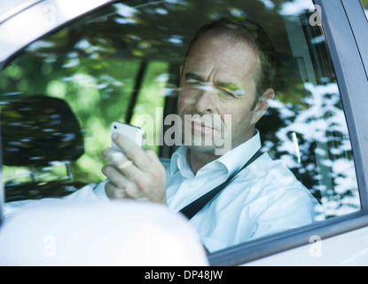 Imprenditore utilizzando il telefono cellulare mentre si guida, Mannheim, Baden-Württemberg, Germania Foto Stock