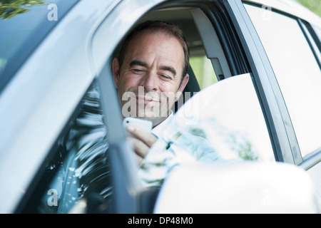 Imprenditore utilizzando il telefono cellulare mentre si guida, Mannheim, Baden-Württemberg, Germania Foto Stock