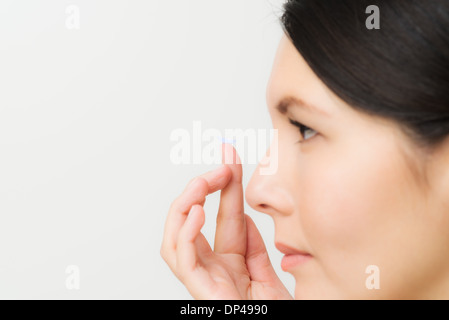 Donna che sta al posto di una lente a contatto nel Suo occhio Foto Stock