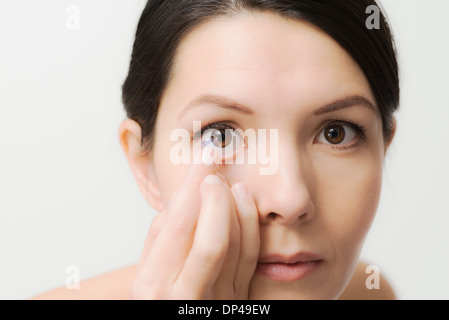 Donna che sta al posto di una lente a contatto nel Suo occhio Foto Stock