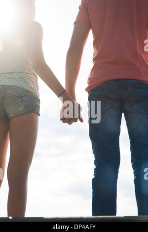 Backview del ragazzo adolescente e ragazza adolescente tenendo le mani in piedi all'aperto, Germania Foto Stock