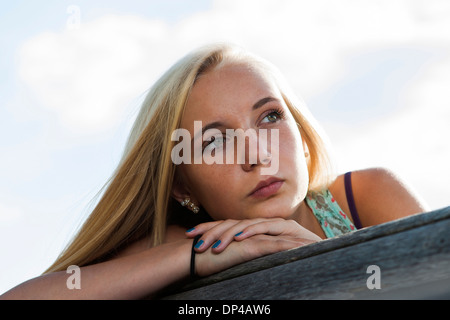 Ritratto di ragazza seduta sul banco di prova all'aperto, guardando in lontananza, Germania Foto Stock