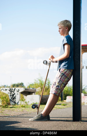 Ritratto di ragazzo all aperto con lo skateboard, permanente sulla strada, Germania Foto Stock