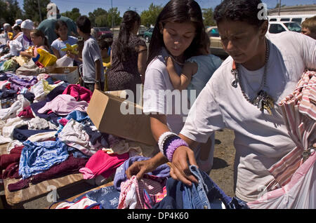 Aug 16, 2006; Sacramento, CA, Stati Uniti d'America; Melany Rogers, a sinistra contiene la sua nipote Miquia Benvenuto, 1, mentre ella ordina anche se le pile di abbigliamento bambino con sua madre Herminia Cruz, a destra. Un 'mobile mall' abbigliamento libero giveaway di bisognosi residenti di Sacramento è il frutto del Padre Dan Madigan, fondatore del Sacramento Food Bank. Il premio si è tenuta mercoledì, 16 agosto 2006 nel del pa Foto Stock