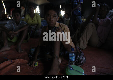 Sep 06, 2006; Banda Aceh, INDONESIA; Indra, a tredici anni profughi di Aceh si siede all'interno di una tenda a Gue Gajah rifugi camp. Egli si rifugiò come il terremoto seguito da tsunami ha colpito tutto il paese compresa la sua casa di Pulo Aceh, due ore di barca dalla città di Banda Aceh. Egli è stato trovato presso la collina dopo flottanti. Ha perso i suoi genitori. Attualmente il suo zio e un vecchio sis Foto Stock