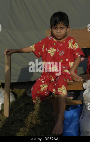 Sep 06, 2006; Banda Aceh, INDONESIA; Molidiye, un bambino di sei anni rifugiato si siede al di fuori di una tenda al Gue Gajah rifugi camp. La sua famiglia è sopravvissuto come sono andati su per la montagna quando lo tsunami ha colpito la sua casa di Pulo Aceh villaggio, due ore di barca dalla città di Banda Aceh. Hanno soggiornato per cinque giorni nell'isola poi recuperati ai rifugi camp. Secondo Wardiyah, zia lei pianse quando il suo Foto Stock