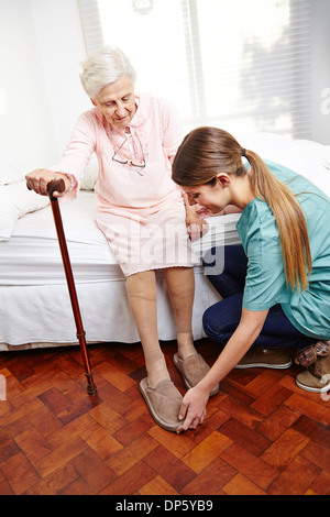 Il caregiver consente di medicazione senior citizen donna sul suo letto a casa Foto Stock