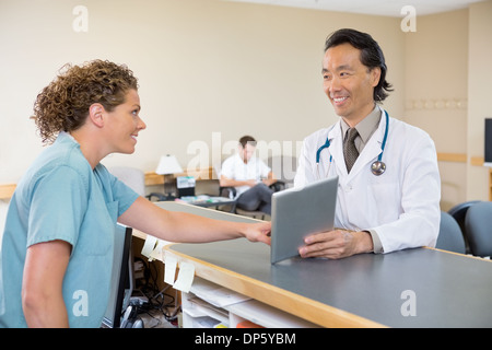 Medico e infermiere con tavoletta digitale all'Ospedale Reception Foto Stock