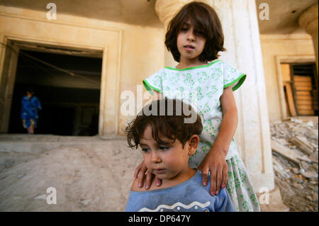 Ott 06 2006, Baghdad, Iraq; una ragazza irachena e suo fratello stare alla porta delle rovine di Saddam Hussein teatro personali a Baghdad. I bambini e le loro famiglie sono state sfollate durante l'invasione 2003 e vivere nel guscio del teatro insieme con diverse altre famiglie. Il teatro fu costruito per intrattenere l'ex presidente iracheno con giochi e spettacoli durante il suo rul Foto Stock