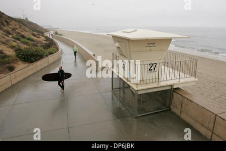 Oct 16, 2006; Carlsbad, CA, Stati Uniti d'America; Drizzly tempo grigio copre la costa come Carlsbad surfer KEITH SCHILLER passeggiate attraverso il Carlsbad Sea Wall dopo l'uscita dell'acqua e il surf onde piccole. Credito: Foto di Charlie Neuman/SDU-T/ZUMA premere. (©) Copyright 2006 by SDU-T