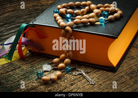 La Santa Bibbia con i grani del rosario su sfondo di legno Foto Stock