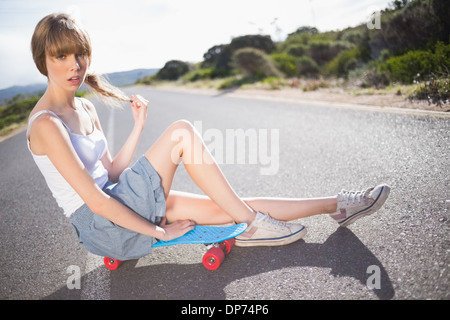 Busbana francese funky bionda seduta sul suo skateboard Foto Stock