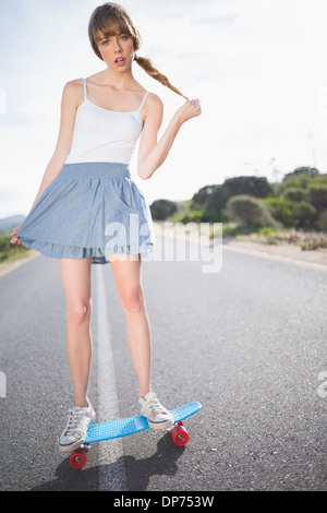 Moda giovane donna il bilanciamento sul suo skateboard Foto Stock