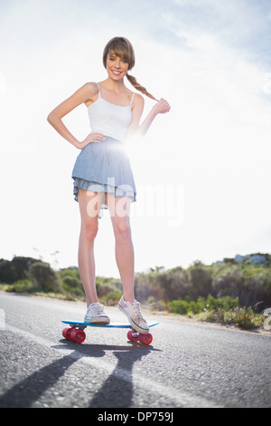 Felice giovane donna il bilanciamento sul suo skateboard Foto Stock