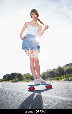 Stupito giovane donna il bilanciamento sul suo skateboard Foto Stock