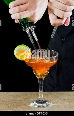 Azione girato di un barman versando red margarita utilizzando più bottiglie Foto Stock