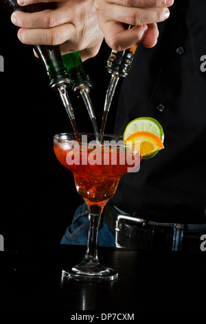 Azione girato di un barman versando red margarita utilizzando più bottiglie Foto Stock