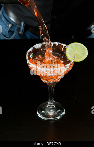 Azione girato di un barman versando un rosso margarita Foto Stock