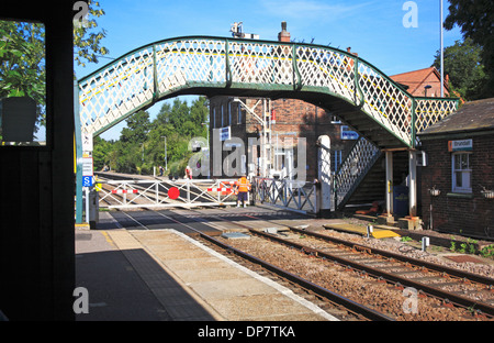 Una vista della stazione ferroviaria con un ponte pedonale e il passaggio a livello Brundall, Norfolk, Inghilterra, Regno Unito. Foto Stock