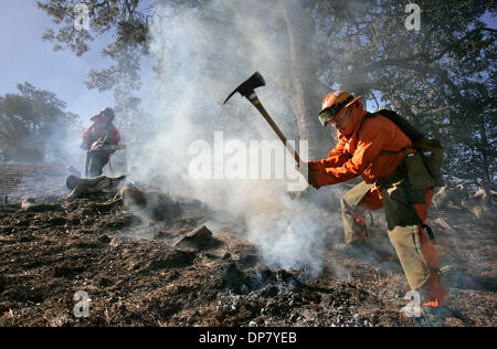 30 nov. 2006; Santa Ysabel, CA, Stati Uniti d'America; vigili del fuoco DEBBIE LAIR, a rotazione a destra di un attrezzo Pulaski e VERONICA QUEVEDO, a sinistra con una motosega, mettere fuori un 'smokey,' ancora un-burning hot spot tra un gruppo di alberi di quercia vicino al fuoco di origine in cui una linea di alimentazione è stata soffiata in venti pesanti questa mattina. Credito: Foto di Charlie Neuman/SDU-T/ZUMA premere. (©) Copyright 2 Foto Stock