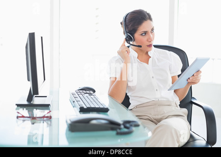 Focalizzato call center agent utilizzando la sua tavoletta digitale su una chiamata Foto Stock