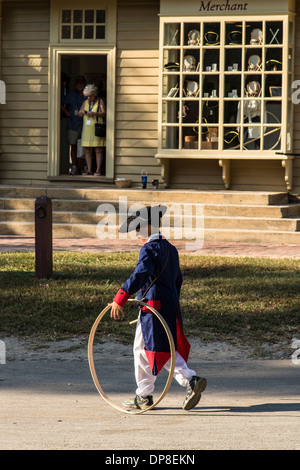 Williamsburg Coloniale costume ragazzo usando un epoca coloniale hoop giocattolo in strada al di fuori di Wm. Pitt store Foto Stock