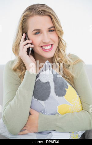 Sorridente bella bionda al telefono seduto sul divano accogliente Foto Stock