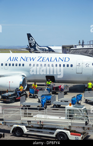 I gestori dei bagagli valigie di carico su un Aria Nuova Zelanda aeromobili all'aeroporto di Auckland. Isola del nord, Nuova Zelanda. Foto Stock