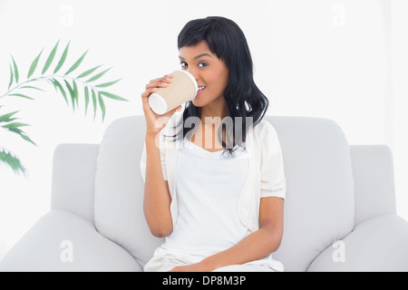 Pacifico dai capelli neri donna in bianche vesti di bere una bevanda Foto Stock