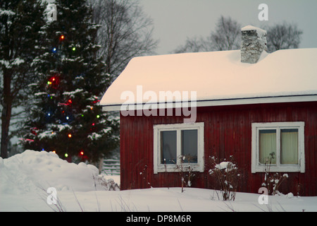 Casa in legno rosso con sensazione di Natale in inverno nordico con la neve Foto Stock