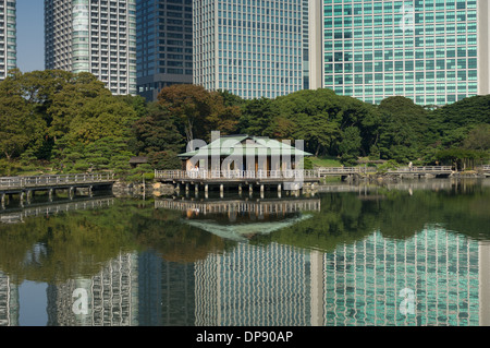 Nakajima Tea House tra le riflessioni di Shiodome skyline nel laghetto Shioiri, Hama Rikyu Teien (Hamarikyu giardino separato), Tokyo, Giappone Foto Stock