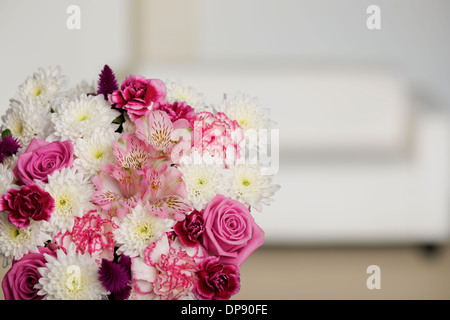 Bouquet di fiori rosa e bianchi in una impostazione di camera con una crema divano letto o divano in background Foto Stock