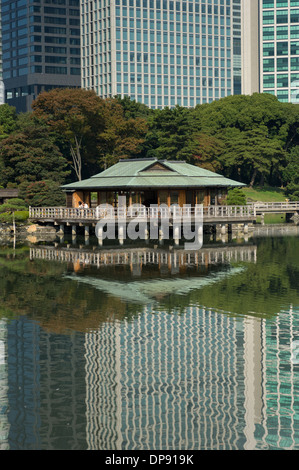 Nakajima Tea House tra le riflessioni di Shiodome skyline nel laghetto Shioiri, Hama Rikyu Teien (Hamarikyu giardino separato), Tokyo, Giappone Foto Stock