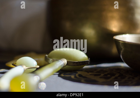 Jade rulli impiegati in naturale massaggio viso accanto alle campane tibetane Foto Stock