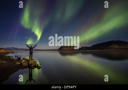 Donna godendo la vista delle luci del nord, presso il lago Thingvellir, Islanda. Foto Stock