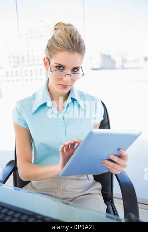 Grave imprenditrice indossando occhiali che usano tablet Foto Stock