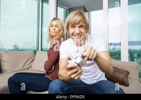 Arrabbiato donna che guarda l'uomo video gioco nel salotto di casa Foto Stock