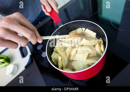 Sezione mediana dell'uomo cucinare la pasta sulla stufa in cucina Foto Stock