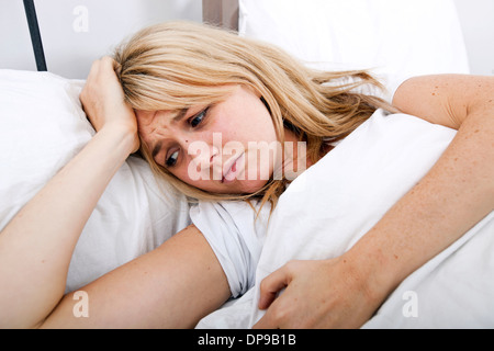 Giovane donna che soffre di mal di testa nel letto Foto Stock