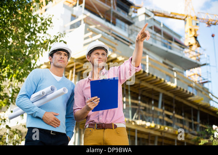 Gli architetti di sesso maschile con blueprint e appunti lavorando presso il sito Foto Stock