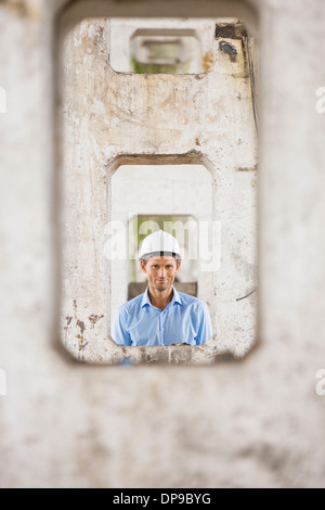Ritratto di architetto maschio attraverso colonne al sito in costruzione Foto Stock