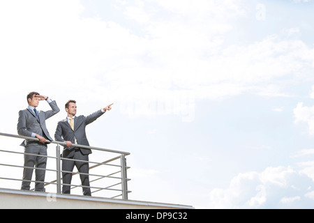 Imprenditore mostrando qualcosa da un collega contro il cielo nuvoloso Foto Stock