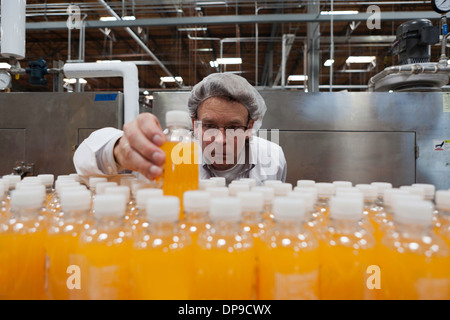 Operaio industriale esaminando bottiglia in fabbrica Foto Stock